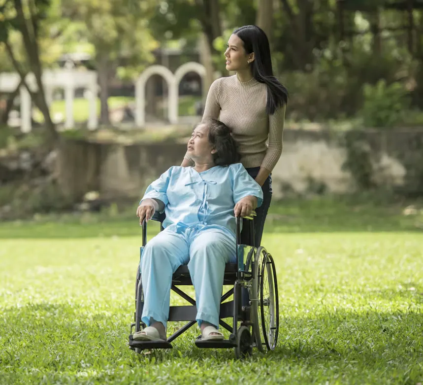 An older woman in a wheelchair enjoying time in a park with her carer